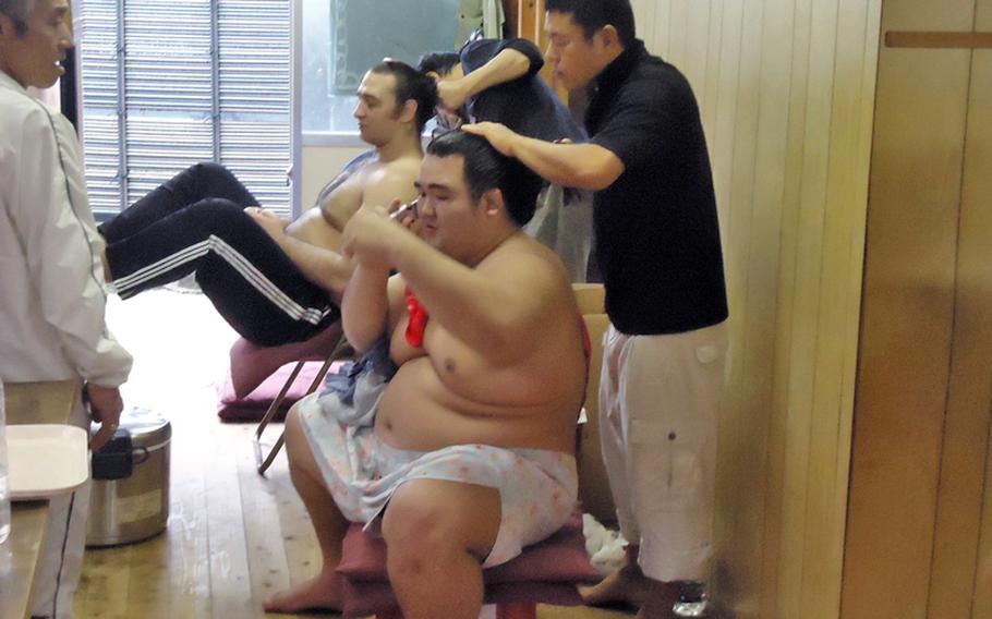 The two famed ozeki Kotooshu, left, and Kotoshogiku, from the Sadogatake sumo wrestler stable in Fukuoka get their hair done after a morning traning session.