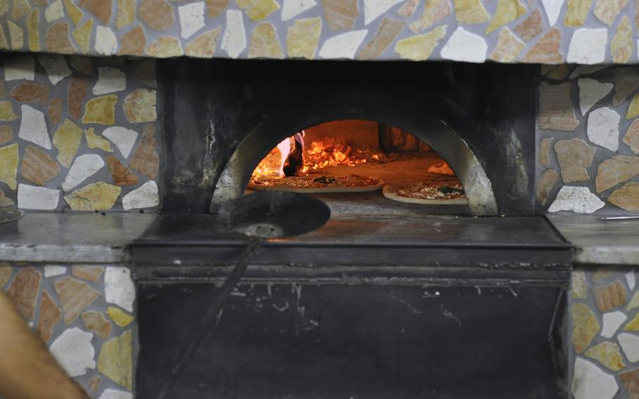 Pizzas cook inside the wood-burning oven at Pizzeria Il Panda in the Naples suburb of Licola.