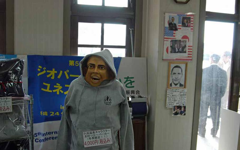 A Halloween mask of President Barack Obama is crudely positioned atop a manequin selling sweatshirts in the tourist information center in Obama. Other memorabilia regarding the president can be seen in the background.