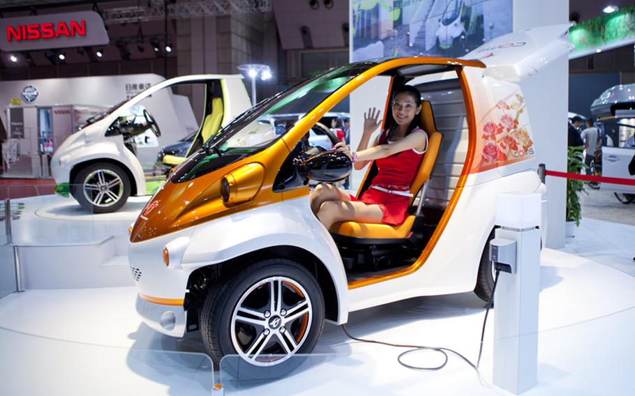 A model waves from Toyota’s plugged-in EV COMS concept car.