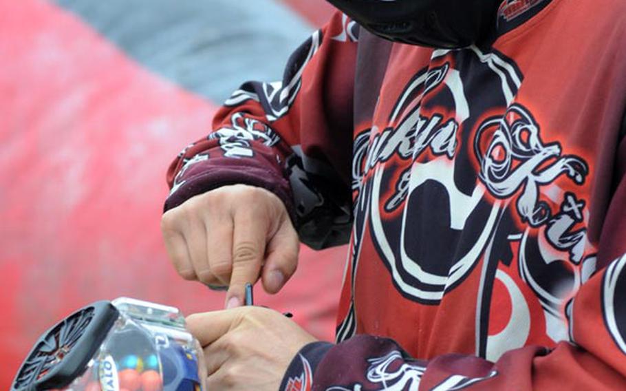 A Ryukyu Kings player performs some quick maintenance on his paintball gun before heading into the paintball field on Kadena Air Base. The Ryukyu Kings were playing fast games, called speedball paintball, which last about two minutes, during the Feb. 25, 2012, session.