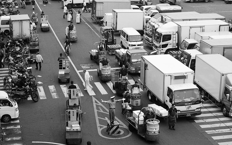 A police officer directs traffic at the chaotic Tsukiji Fish Market.