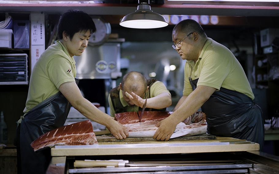 Workers cut tuna in the inner portion of the market, which opens to the public at 9 a.m.