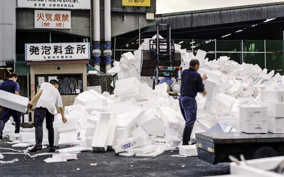 Fish market employees collect insulated boxes to store fish.