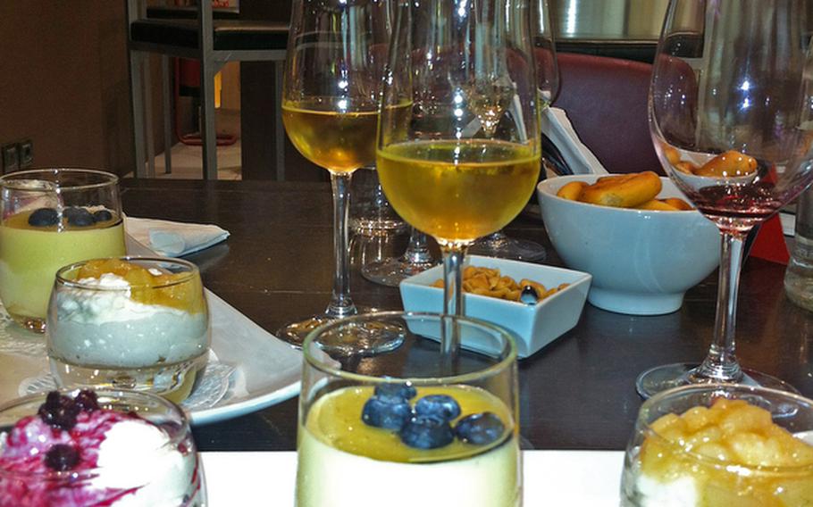 A glass of  Privilegio Fiano Passito Irinia DOC, a dessert wine, is served with a sample of whipped buffalo cheese mousse with cherry topping, far left; a sweet Italian custard "zabaglione" topped with fresh blueberries; and whipped buffalo cheese mousse topped with spiced pear. The sweet wine sells for 4 euros a glass or 33 euros for a bottle at the Feudi di San Gregorio Wine Bar in the Vulcano Buono shopping mall in Nola, Italy.