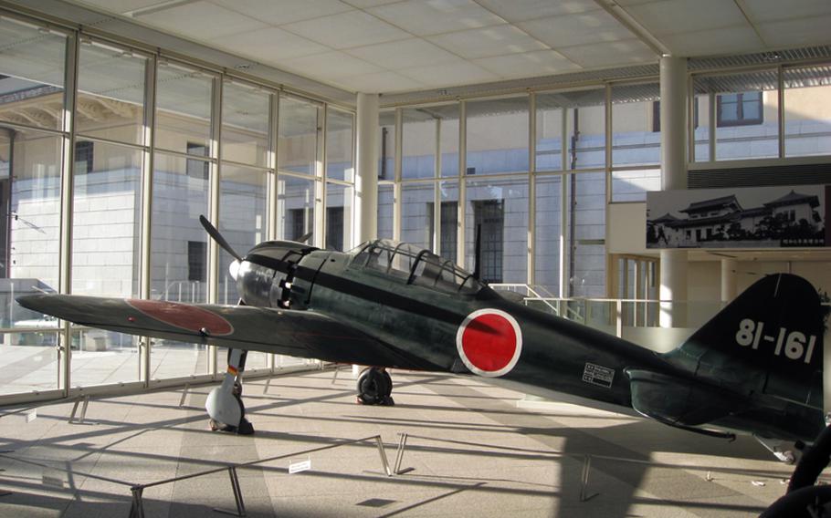 A Mitsubishi-made Zero fighter aircraft faces the setting sun from within the Yushukan war museum on the grounds of the Yasukuni Shrine.