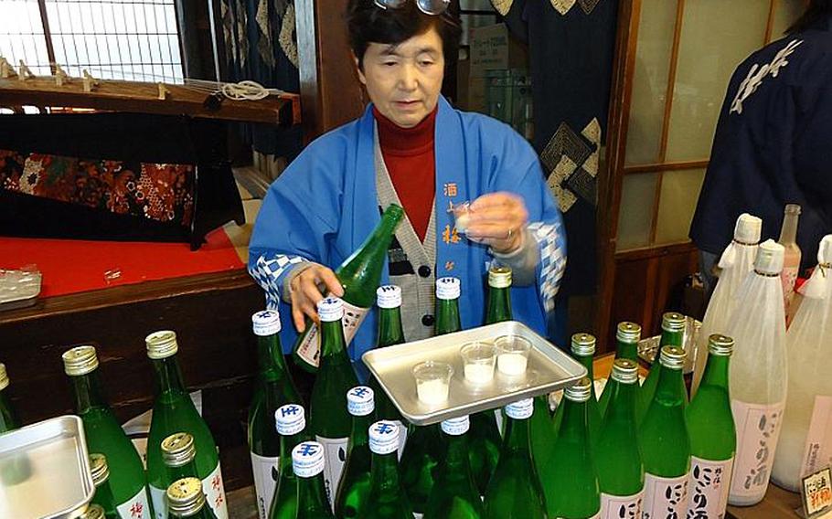 An employee of the Umegae sake brewery in Sasebo provides a sample before buying at a tasting at the brewery on Feb. 9. Breweries across Japan offer tours and tastings upon request.