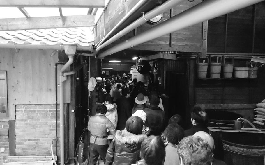 Customers stand in line for freshly bottled sake at the Umegae brewery in Sasebo, Japan.