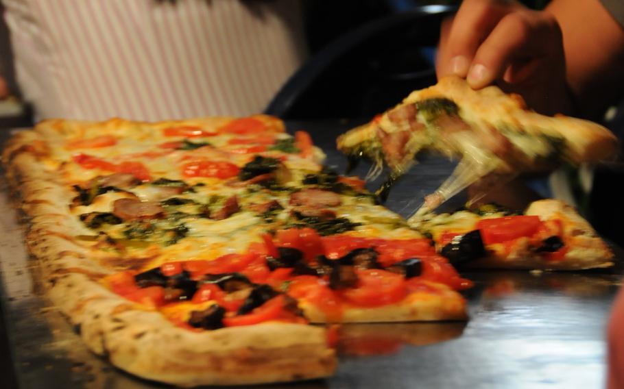 A diner at Il Tucano restaurant and pizzeria in the Naples suburb of Baia snags a piece of vegetable-topped pizza. Restaurant owner Salvatore De Stefano says pizza makers, or "pizzaioli," have a secret behind their delicious dough -- less yeast used and more time to let the dough rise. But he declined to provide further details.