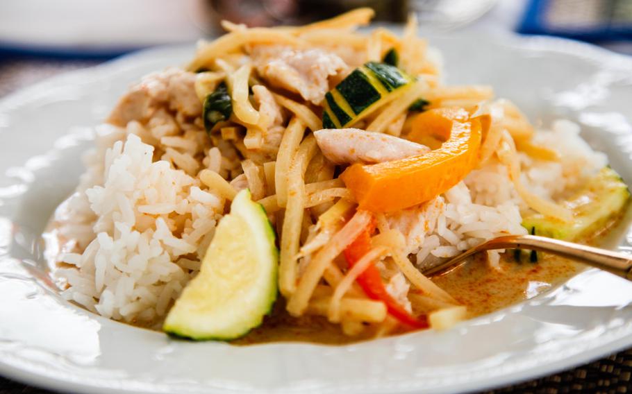 Gang phed gai, a traditional Thai dish of chicken in a red curry with coconut milk and vegetables, served over sticky white rice.