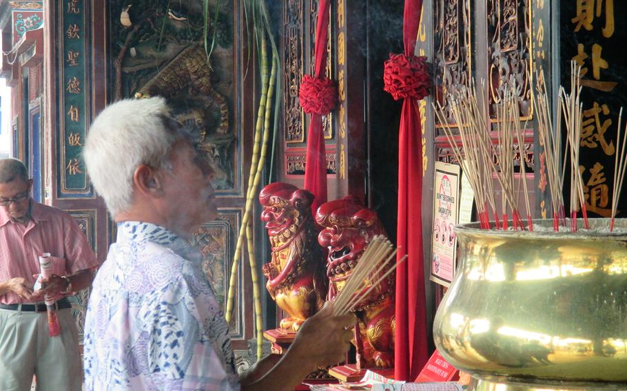 A man waves incense at the Cheng Hoon Teng Temple in Melaka. In addition to this Chinese temple, built in the 1600s, the city has churches and a mosque, reflecting its multcultural heritage.