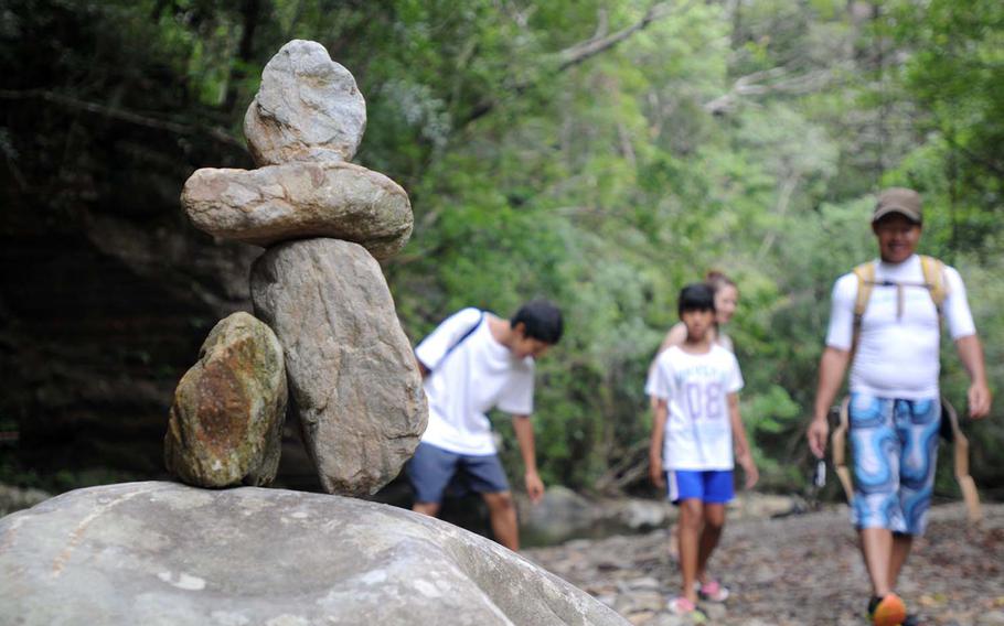 Hikers enjoy making rock art along the riverside trail of Hiji Falls National Park, Okinawa, Japan.