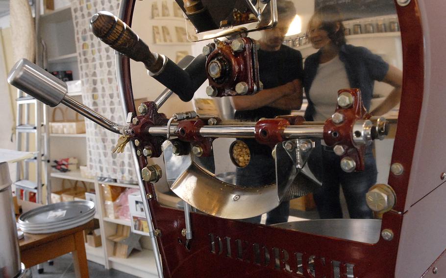 Christian and Stephanie Bebensee, owners of Kaffeerösterei Kaiserslautern, are reflected in the coffee roaster 
that stands in a back room of the cafe.