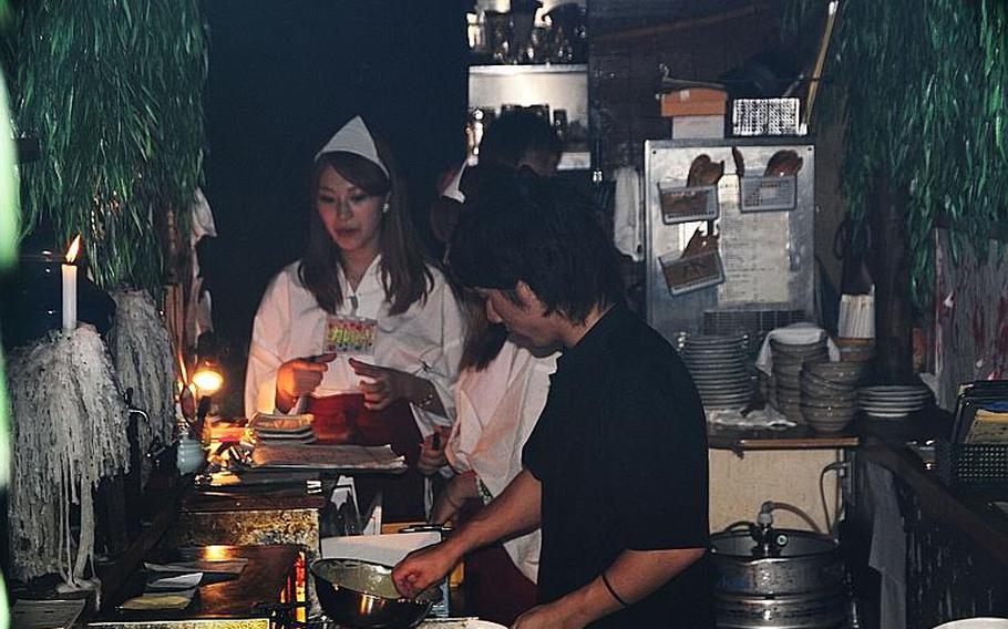 Hell's kitchen: a chef at Yurei prepares a ghost-related dish as waitresses prepare to serve it.