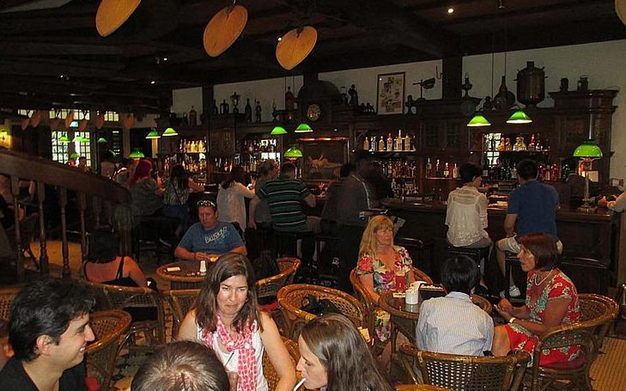 Tourists drink Singapore Slings inside the Long Bar at the Raffles Hotel in Singapore, where the drink was invented.