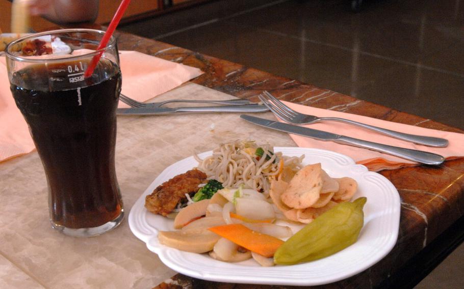 A lunch buffet plate and large soda sit on a table at Restaurant Asia. Restaurant Asia is a popular Asian restaurant and buffet in eastern Kaiserslautern, Germany.