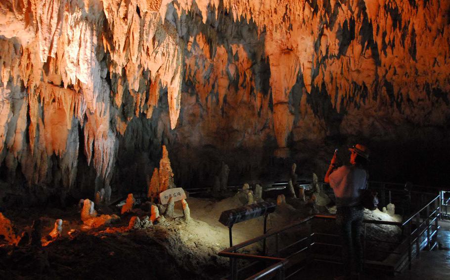 A woman photographs a chamber of stalactites.