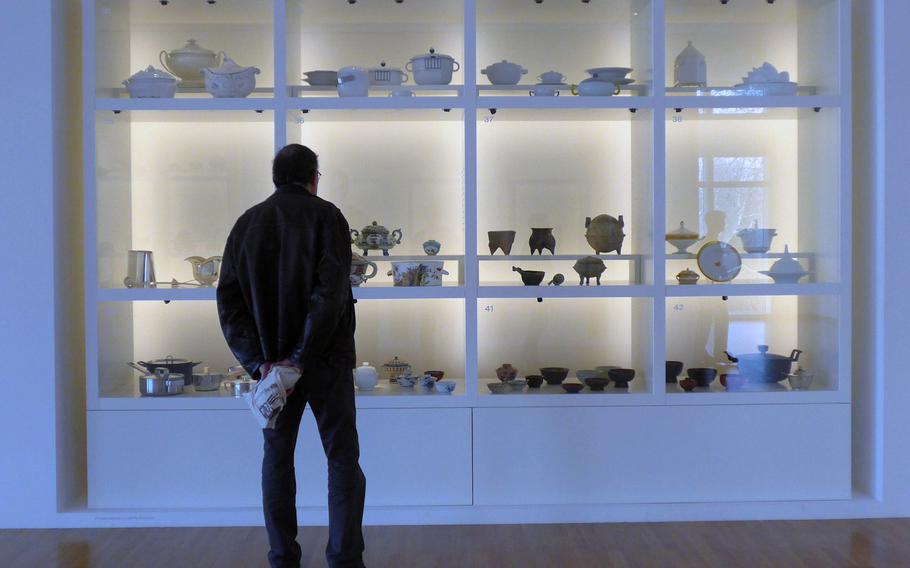 A visitor to Frankfurt's Museum Angewandte Kunst, or Applied Arts Museum,  checks out a display of soup bowls. They are part of a temporary exhibit of soup bowls and utensils through the ages from the museum's depot.