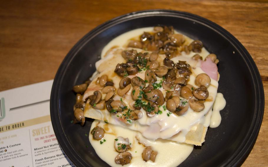 Ham, mushrooms and cheese sauce decorate a waffle from The Waffle House in Norwich, England. The dish is one of several savory lunch or dinner offerings.