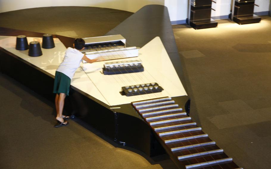 A boy plucks one of the cables that serve as strings on the world's largest electric guitar, according to the Guinness Book of World Records. The one-ton replica of Gibson's legendary Flying V model is the centerpiece of the exhibit at the Bishop Museum in Honolulu.
