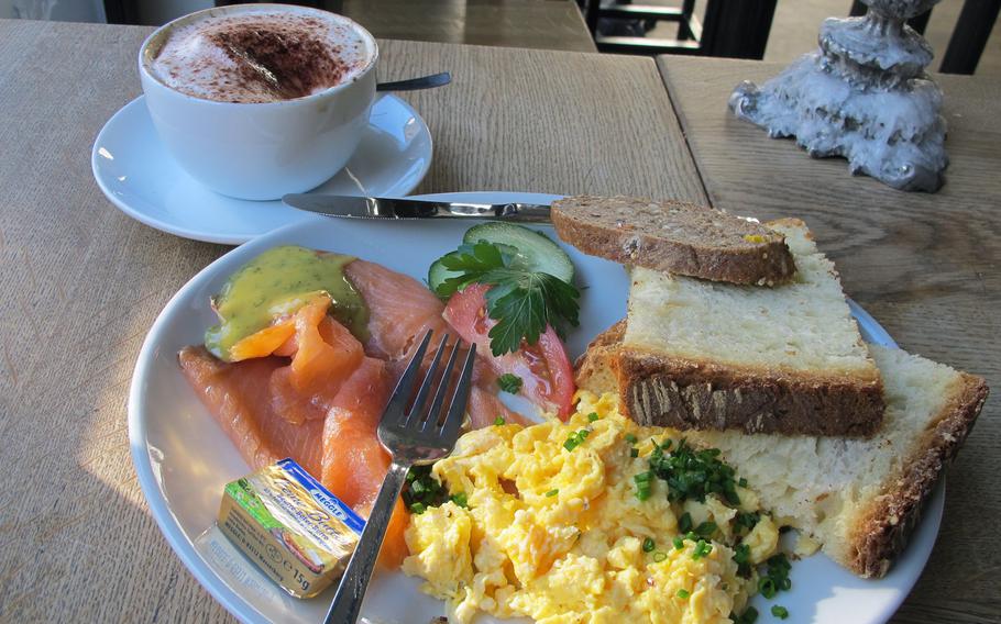 The breakfast menu at Hüftengold, a cafe in downtown Stuttgart, includes scrambled eggs with a variety of sides, such as smoked salmon. The cappuccino is served with a rich cream and melted chocolate.