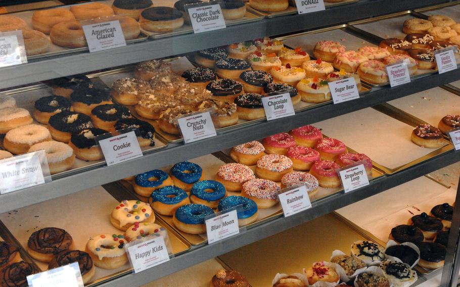 A view of the display case at Happy Donazz, a newly-opened breakfast spot in Kaiserslautern, Germany. The eatery's donut options feature colorful English-language names like Happy Kids, Strawberry Princess, Vanilla Passion and Sugar Bear.