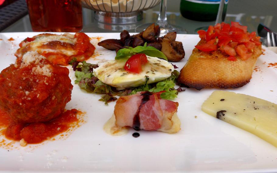 The antipasto della casa at I Trulli, an Italian restaurant in Ramstein, Germany. The assortment of starters differs according to what the chef cooks up. On this day it was, clockwise from bottom left, a meatball in tomato sauce, a bite of eggplant parmigiana, grilled mushrooms, bruschetta, aged pecorino, and warm cheese wrapped in bacon, with a spot of caprese at center.
