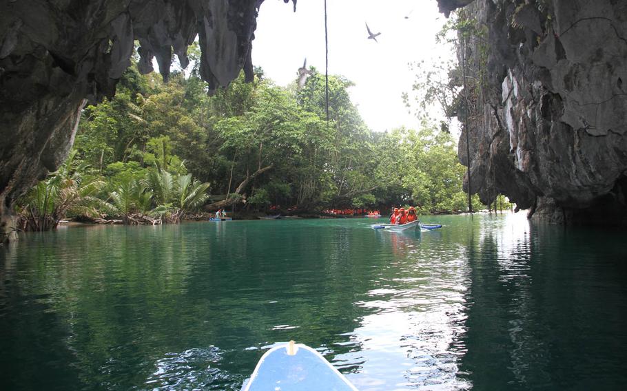 Bats fly over the serene lagoon that  serves as a launch point for tour boats at the Puerto Princesa Underground River in the Philippines. Visitors wear hardhats to shield themselves from the falling dung of thousands of bats that call the cave home.