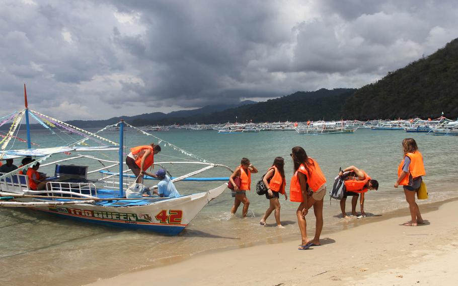 Visitors to the Puerto Princesa underground river arrive at the beach near the cave's entry. In the background are dozens of boats that each day ferry hundreds of people to the UN World Heritage Site in the Philippines.