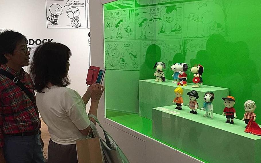 A "Peanuts" fan photographs a toy display at the Snoopy Museum Tokyo, Sunday, May 15, 2016. The temporary museum includes more than 60 original, hand-drawn comic strips by Charles Schulz, creator of iconic characters like Snoopy and Charlie Brown.