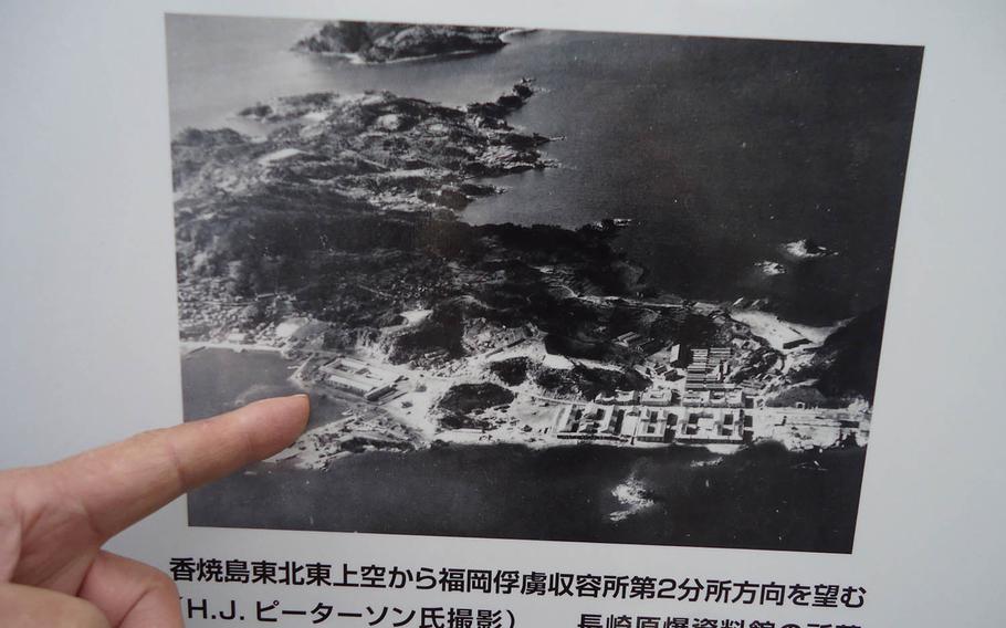 A sign in front of Koyagi Junior High School in southern Nagasaki, Japan, shows an aerial image of Fukuoka Prisoner of War Camp No. 2 at the end of World War II. A monument to the men who perished there during and after the war was erected on the street, just off the school's grounds, in September.