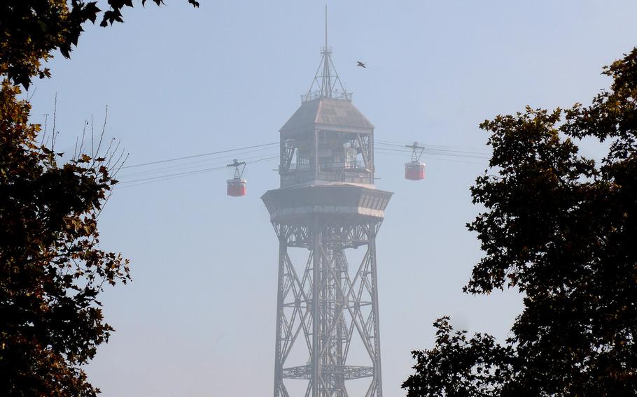Two cars of the Transbordador Aeri del Port, or port cable car, approach the support tower on Barcelona's port as seen from Las Ramblas. The cable car runs from Barceloneta to Montjuic.