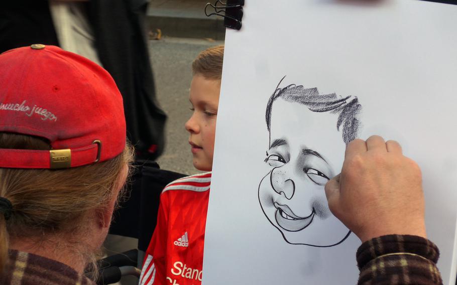 An artist draws a caricature of a boy on Las Ramblas. The Barcelona pedestrian thoroughfare is a magnet for street artists of various kinds hoping to make some change off the thousands of tourists who stroll down it.