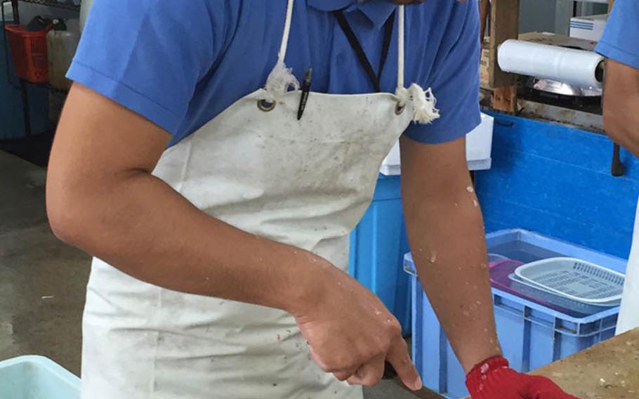 A worker guts a freshly caught fish at the Awase fish market in Okinawa. Nearby, fresh fish is cooked and served at Payao.