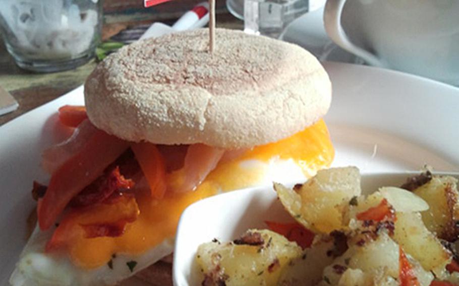 This sandwich at the Santa Monica Pastry Shop in Kaiserslautern, Germany, was served on an English muffin and included a fried egg, smoked salmon, cheese, and sun dried tomatoes. It came with a side of hearty breakfast-style  potatoes.