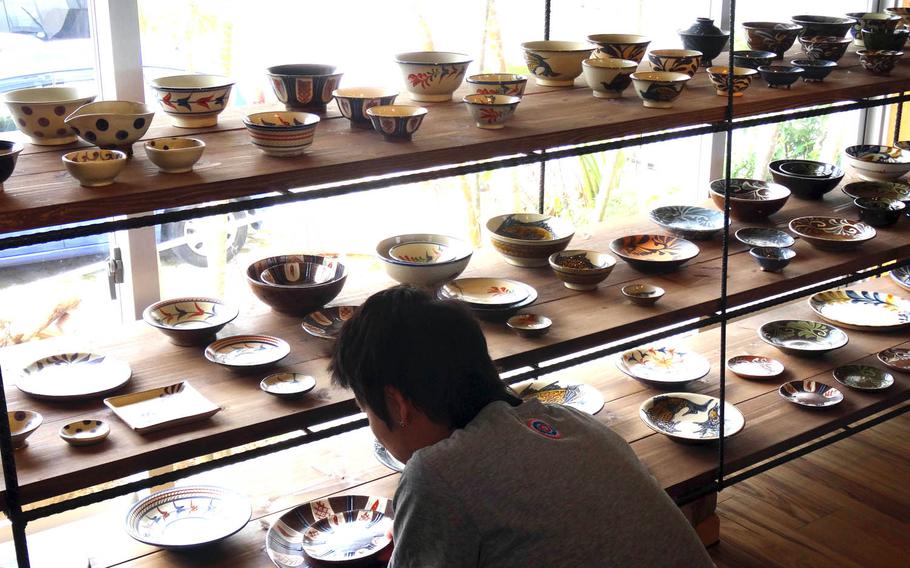 A visitor examines pottery at the gallery inside Pottery and Cafe Gunjo in Okinawa, Japan. Okinawan pottery is known for its  bold use of colors and patterns.