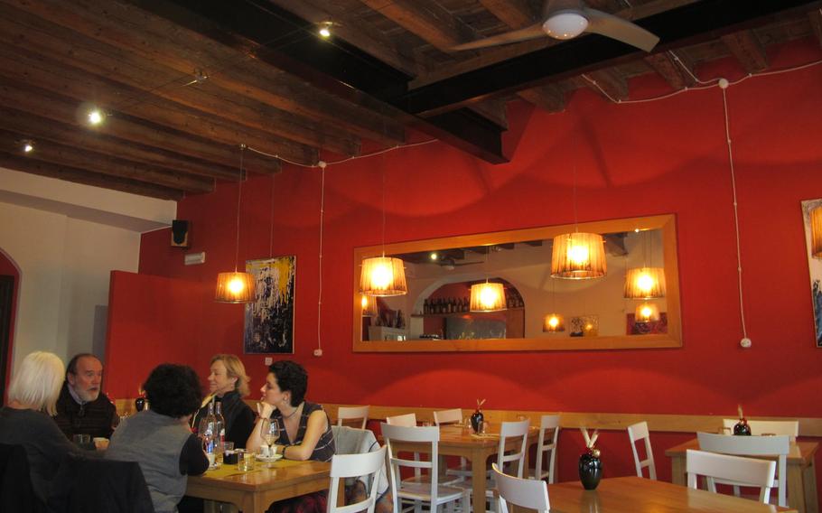 Al Ritrovo's dining room invites with warm red walls, a large mirror and glowing lamps hung from the wood beam ceiling. The restaurant is among several in Vicenza, Italy, that serve traditional regional dishes.