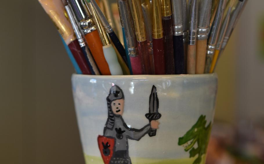 A hand-painted mug holds various paintbrushes at Mal-Werk.