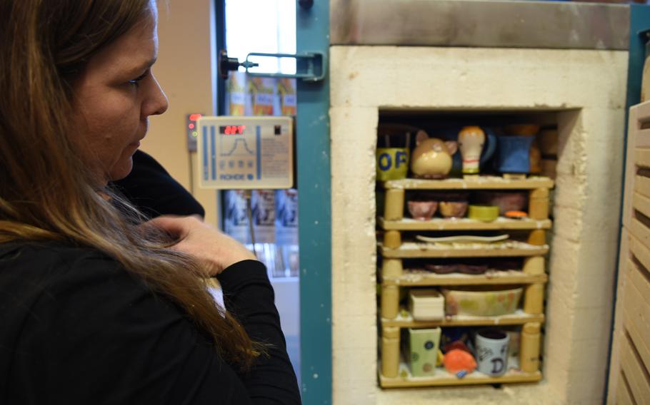 Alexandra Doss, the owner of Mal-Werk, looks inside the shop's kiln, where she fires pieces of pottery hand-painted by customers.