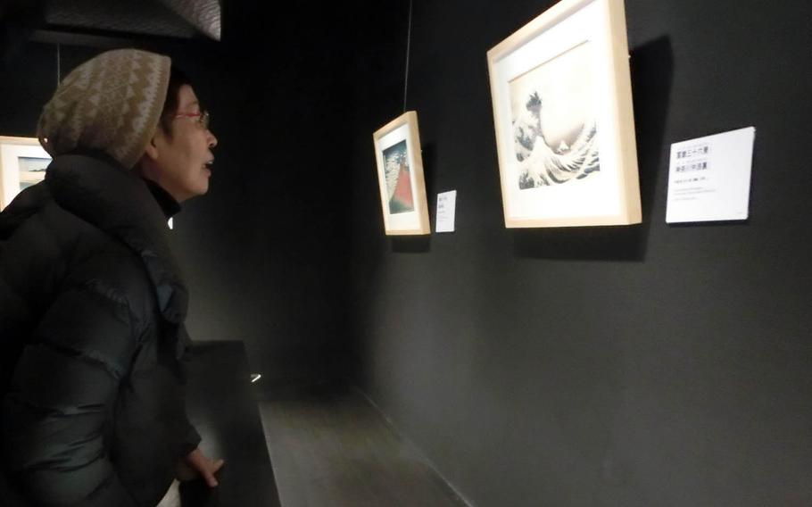 A woman takes a close look at replicas of famous paintings by Katsushika Hokusai at the Sumida Hokusai Museum in Tokyo.