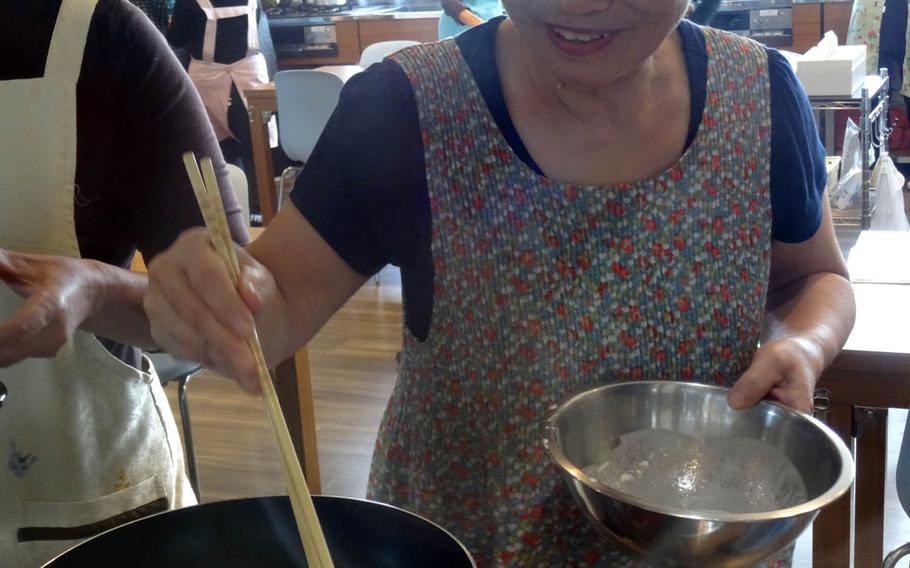 Toshiko Kamiyama is pleased with her success at making kintsuba cakes recently at the Kae Project Cooking School in Yomitan, Okinawa. The cake, made of sweetened purple sweet potatoes, is a Yomitan specialty.