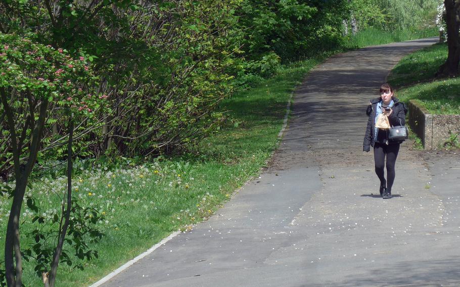 A person walks through the Seewiese, a park along the banks of the Usa, a stream that runs past Friedberg, Germany. With benches and plenty of green, it is also a nice place for a picnic.