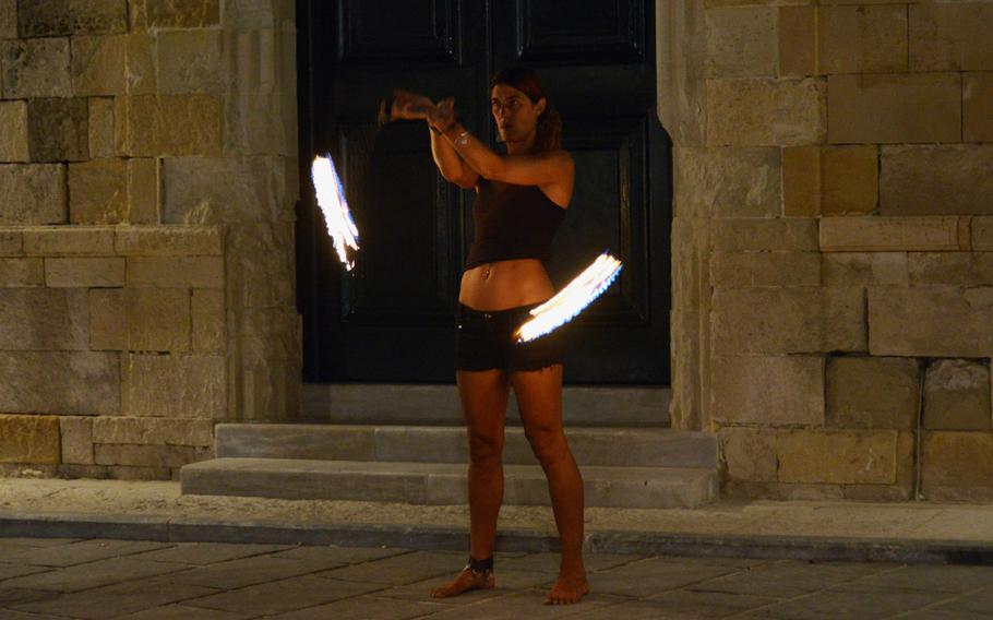 A street performer entertains tourists in Chania, Crete with a fiery performance.