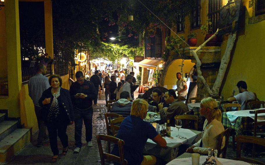 People enjoy a Cretan dinner as others wander along the shop-lined cobblestone alleys in Chania, Crete.