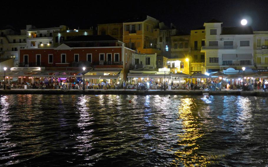 A full moon rises over the houses lining Chania, Crete's Old Port. They are full of shops, restaurants and bars.