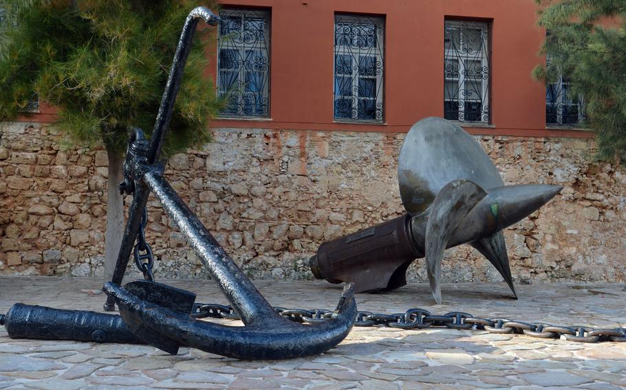 An anchor and a ship's propeller stand in front of the entrance to the Maritime Museum of Crete in Chania.