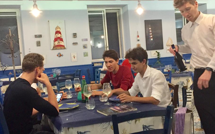 A waiter serves wine to a group visiting from Switzerland at Ristorante I Primi.