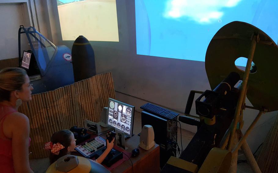 A visitor to the Pacific Aviation Museum in Hawaii tries her hand at one of the flight simulators that depict various battles and scenarios of World War II in the Pacific.