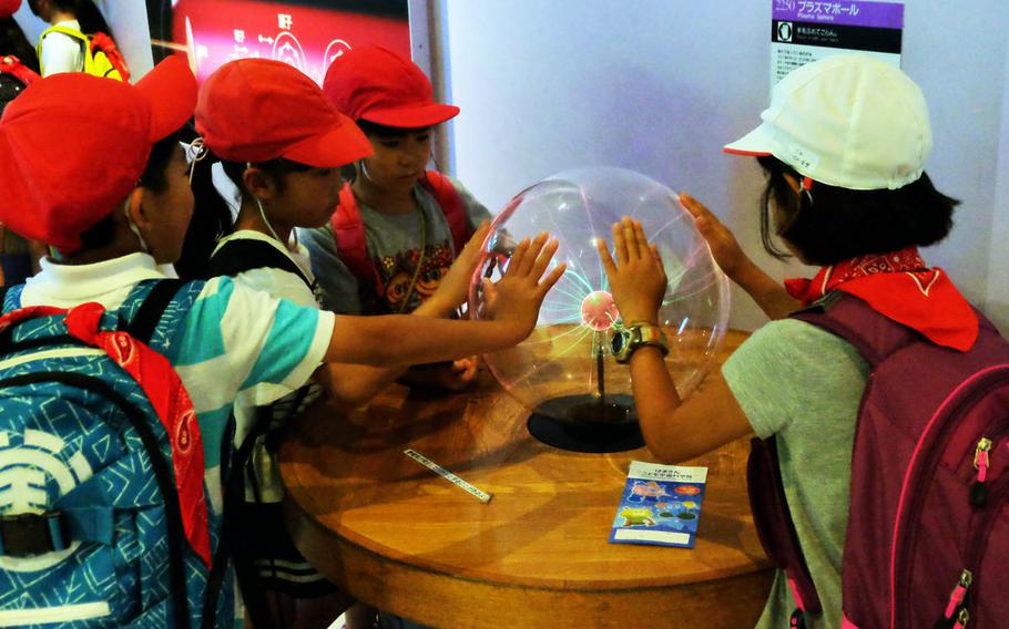 Schoolchildren examine a plasma ball at Hamagin Space Science Center in Yokohama, Japan.