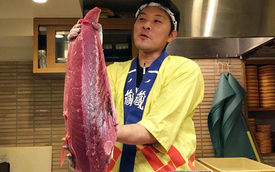A chef holds up a large section of tuna during the nightly carving show at Maguro Shoten, a restaurant in Tokyo's Kabukicho entertainment district.